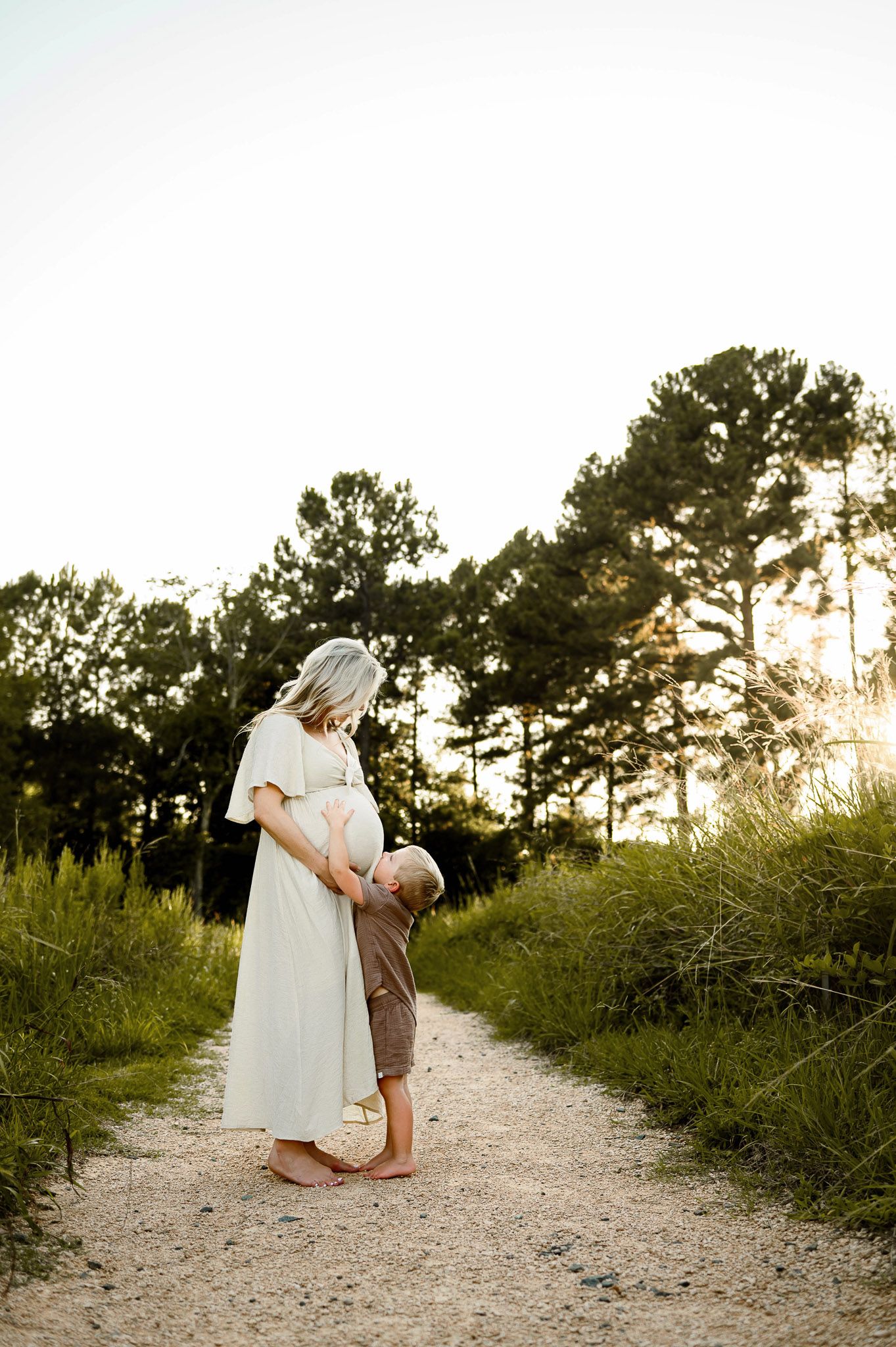 Young child touching his mother's baby bump during an outdoor maternity session in Raleigh NC