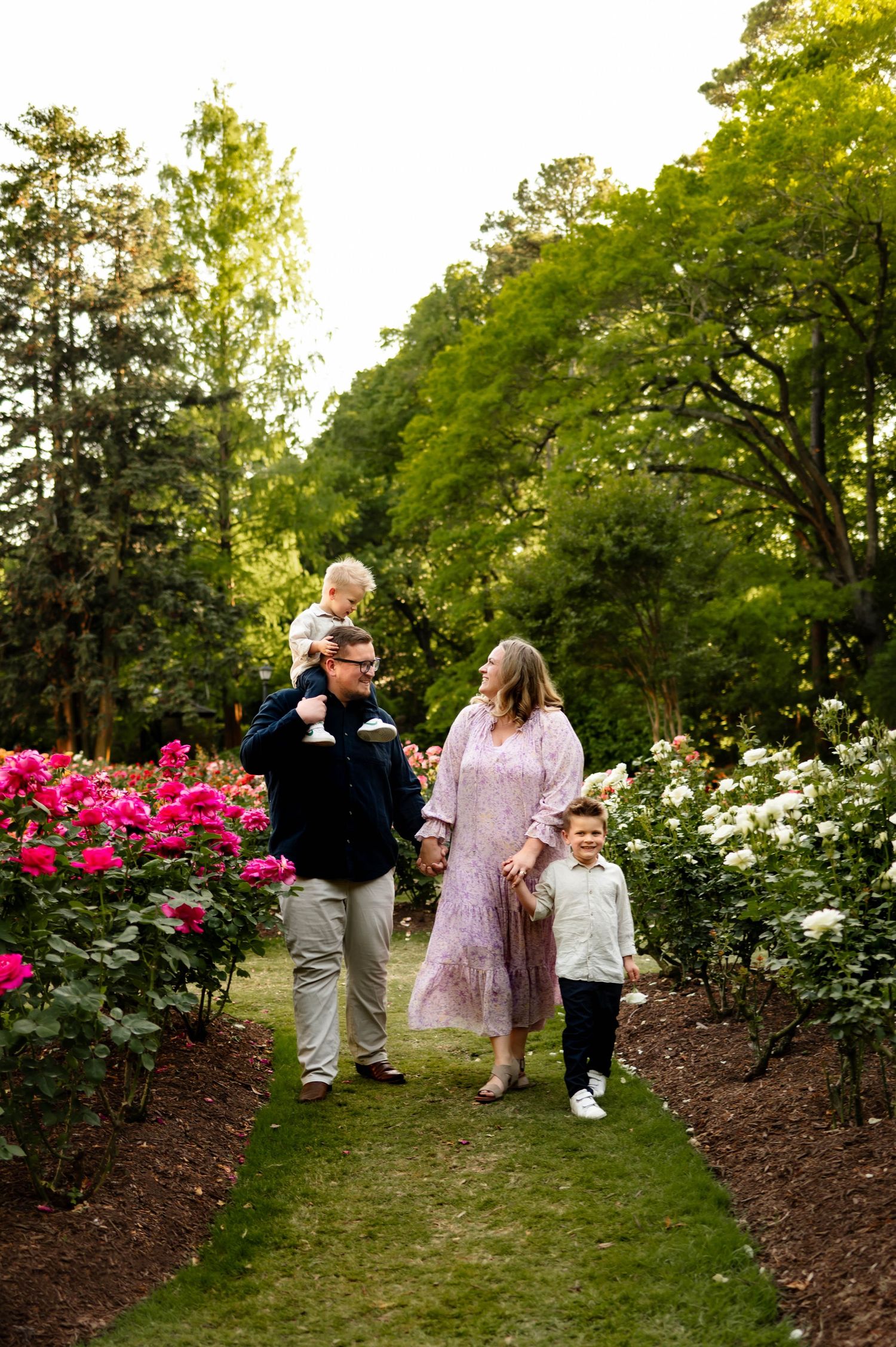 Raleigh family photographer captures a family of four walking together during a spring surrounded by blooming gardens
