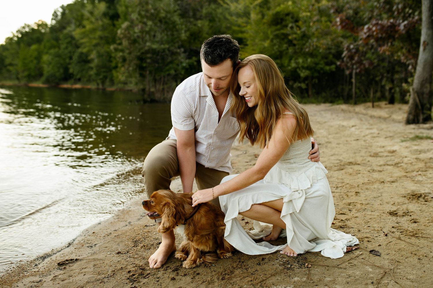 A couple in white outfits sits with their puppy and plays in a joful candid photo taken by Emma Branch Photography in Raleigh NC