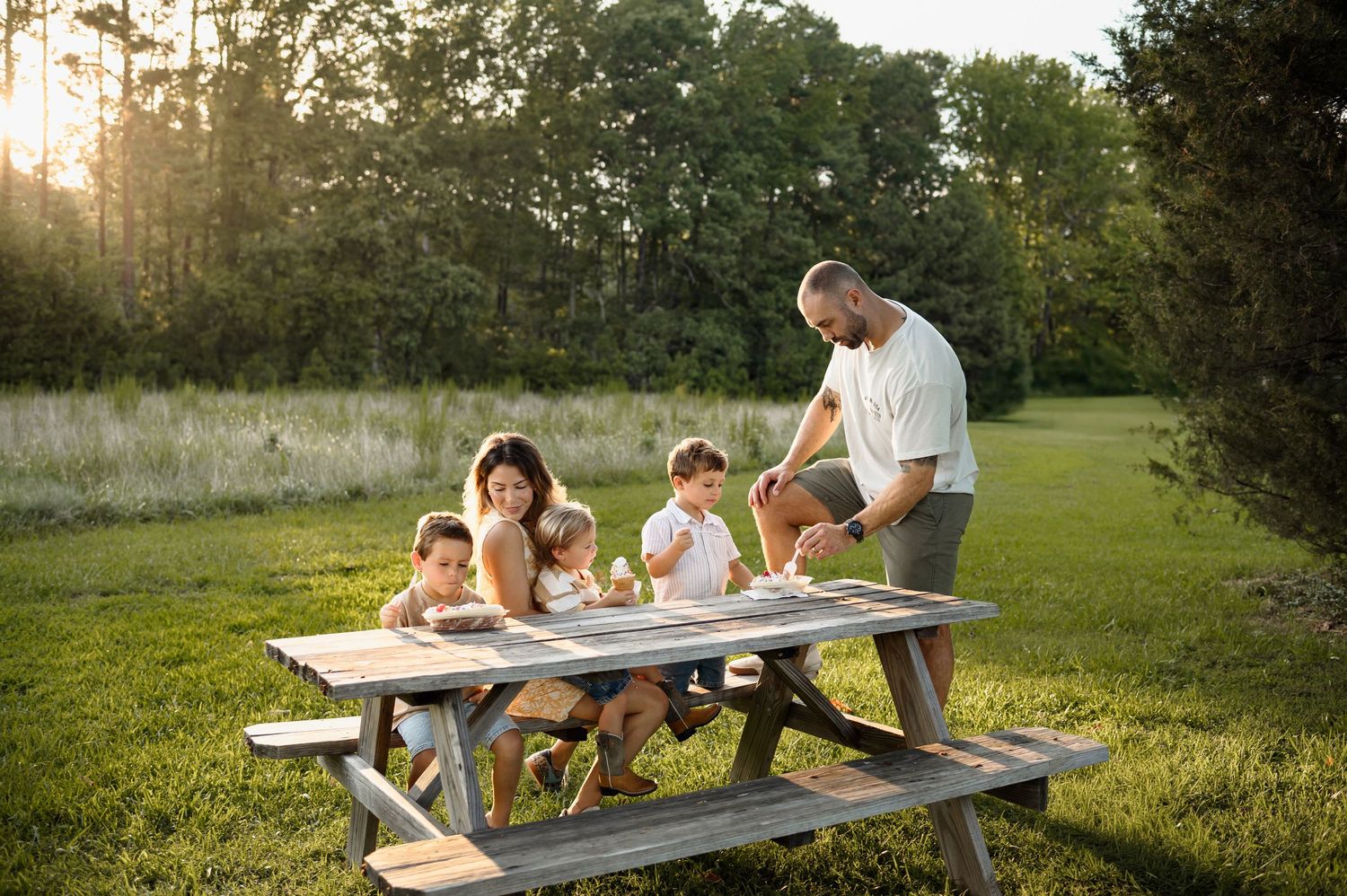 Raleigh family photographer capturing a candid family moment with parents and children at a picnic table during golden hour
