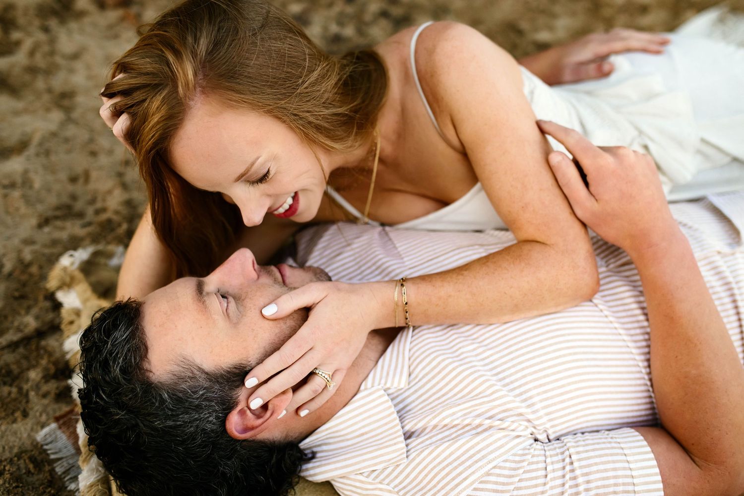 A romantic couple shares an intimate moment together while lying down on a white blanket with family photographer in Wake Forest NC