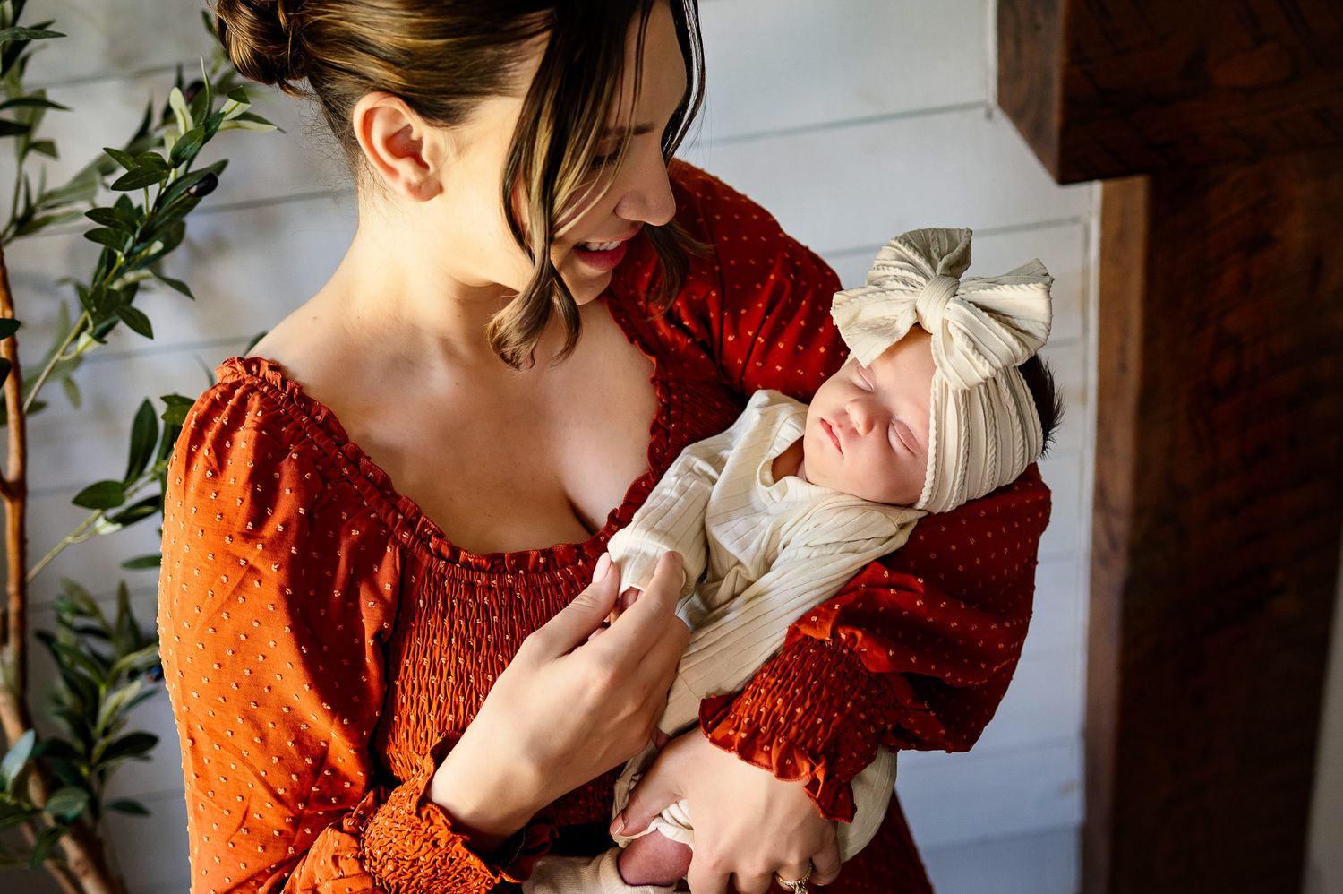 Mother cradling her sleeping newborn baby during a cozy in-home newborn photography session in Wake Forest, North Carolina