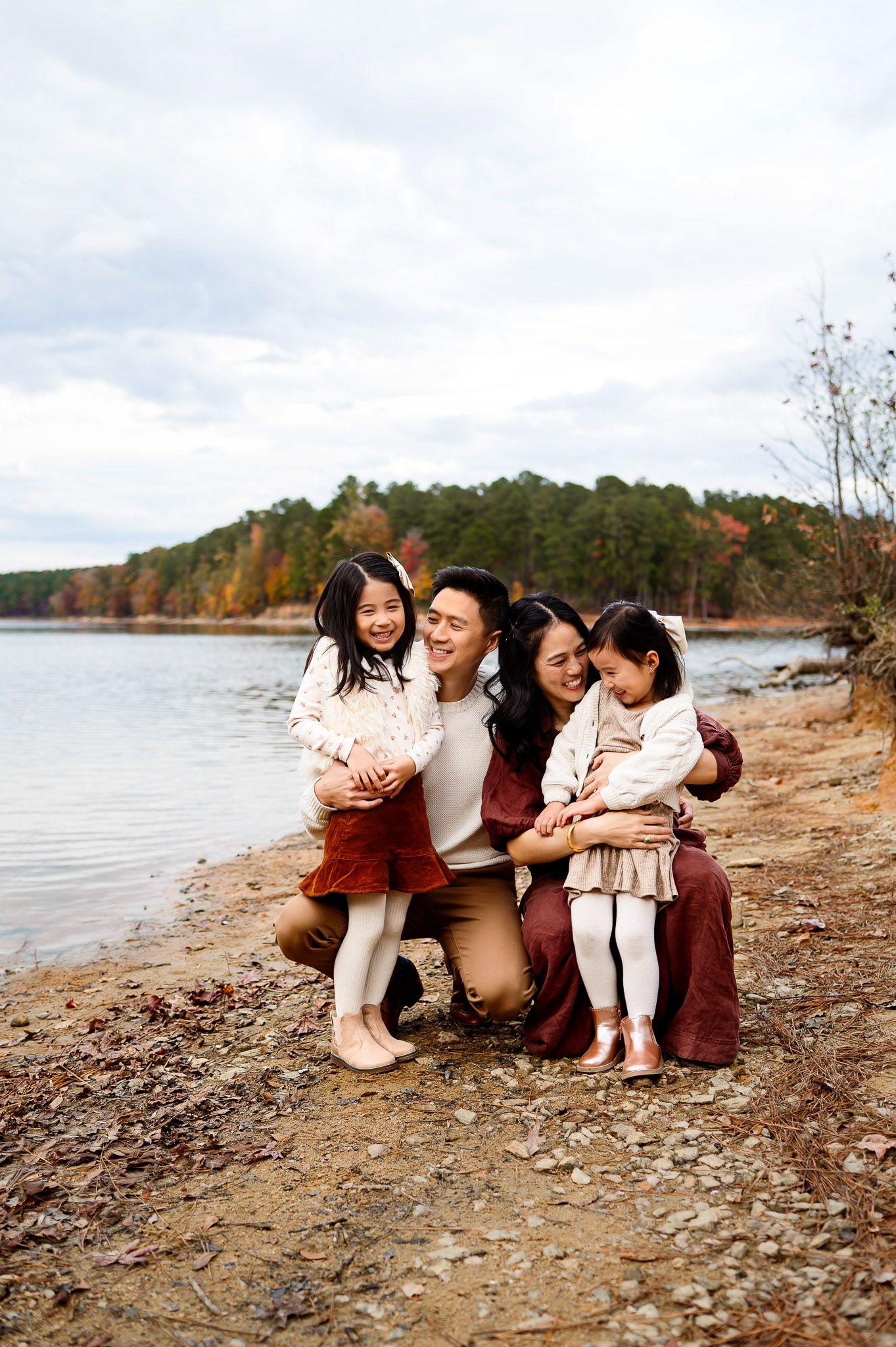 Family of four sitting together along the lakeshore during a fall family photography session