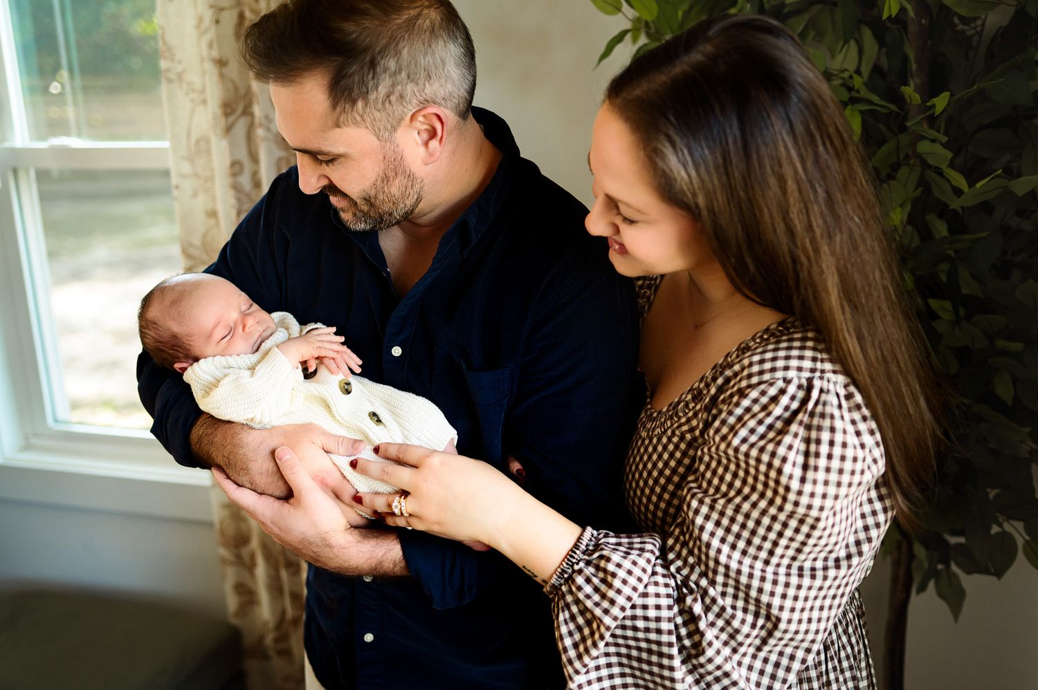Parents looking down at their newborn baby during an intimate in-home newborn photography session in Raleigh NC