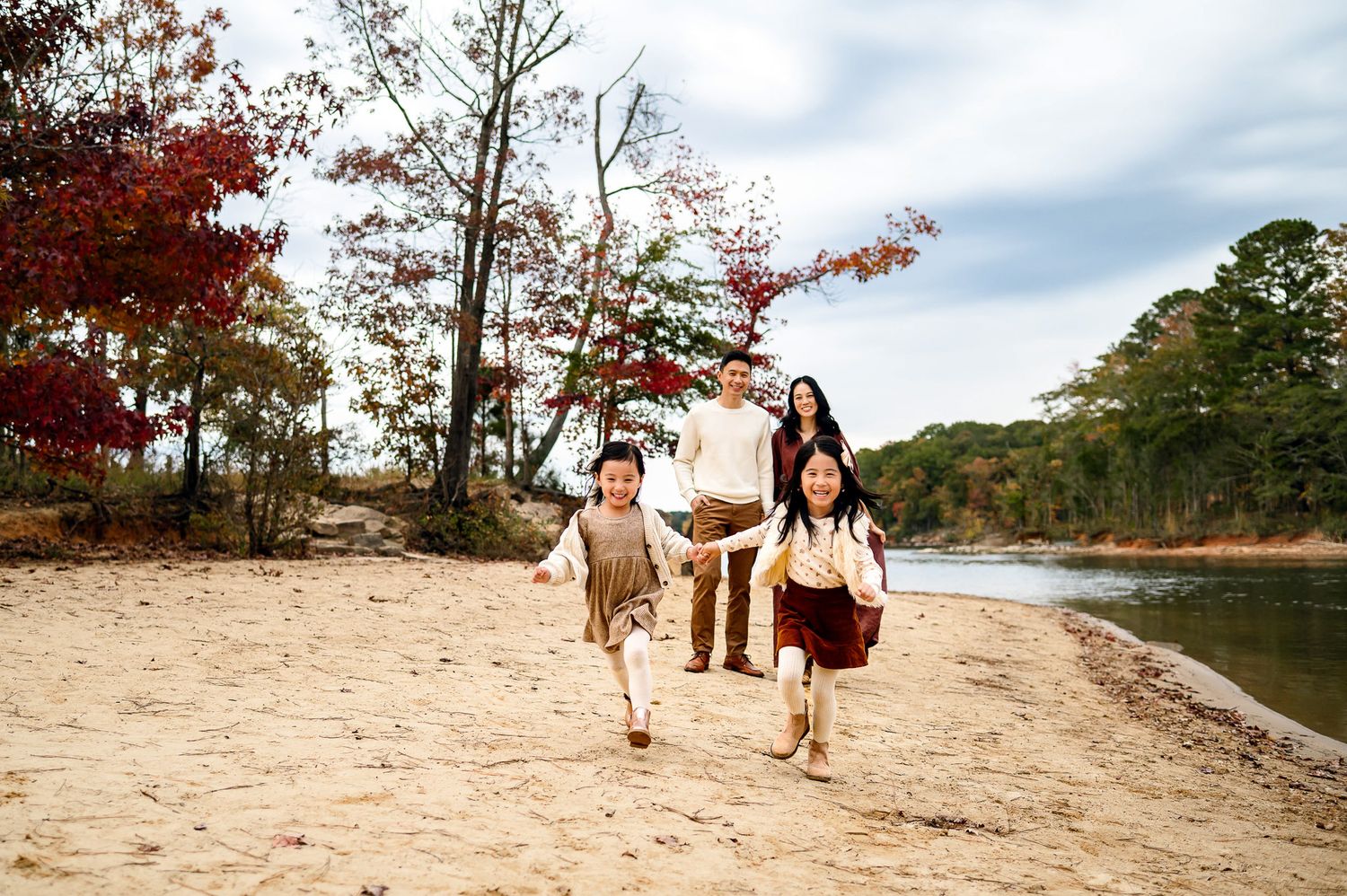 Children running toward the camera while their parents follow behind during a playful outdoor family photography session