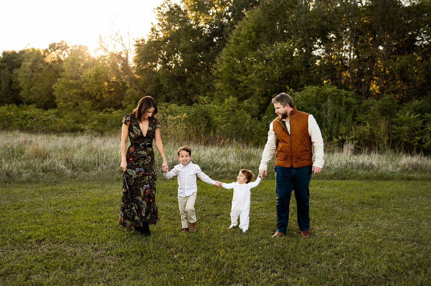 Family walking together through a grassy field during a sunset family photography session at a Raleigh NC photo location