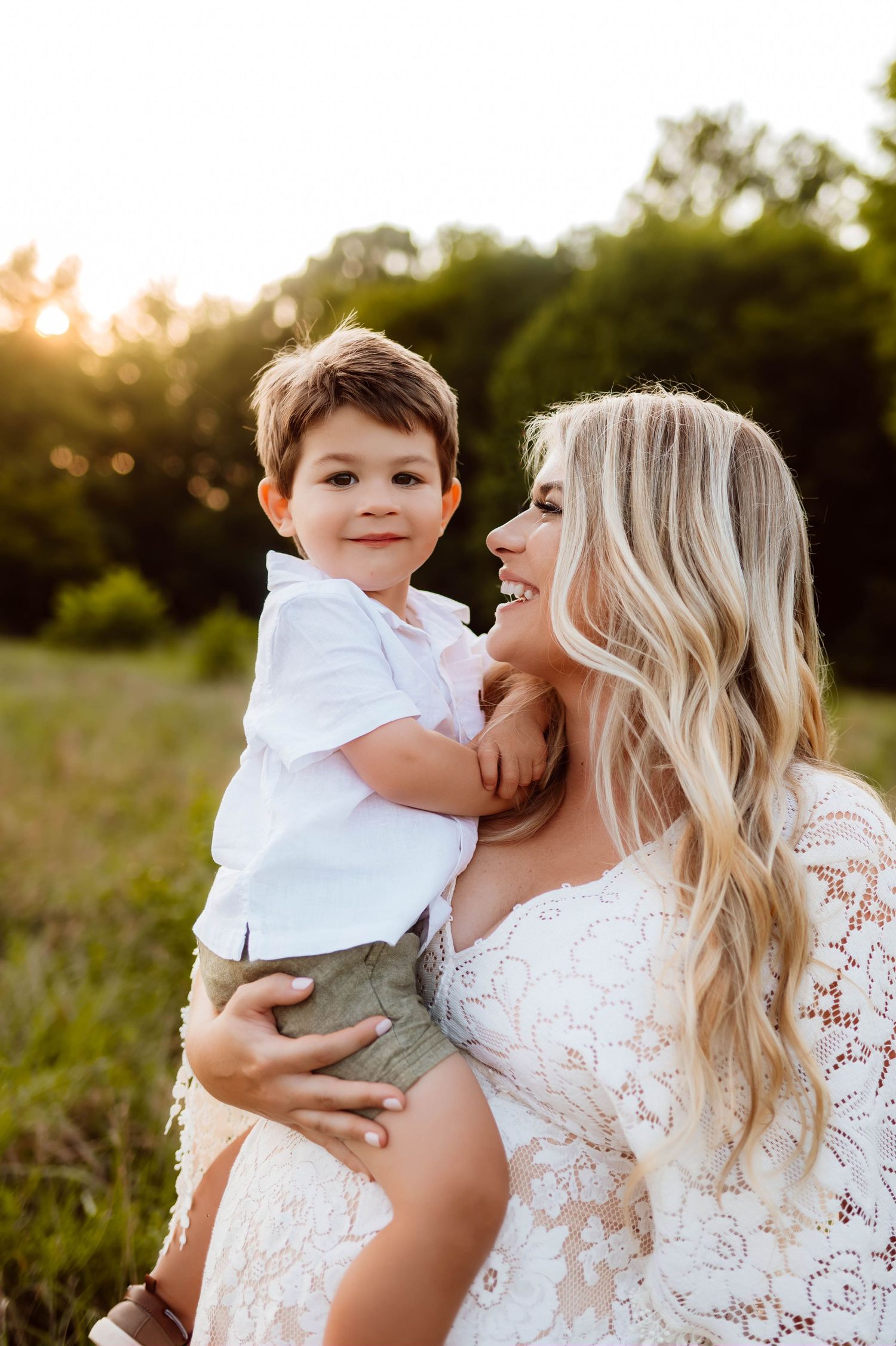 A sweet moment captured between mother and child in a sunlit field at golden hour in Wake Forest for maternity photography shoot