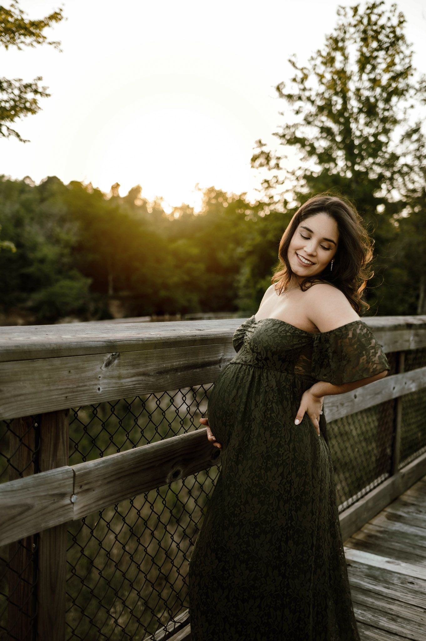 Expectant mother leaning on a wooden bridge during golden hour maternity photography in Raleigh NC