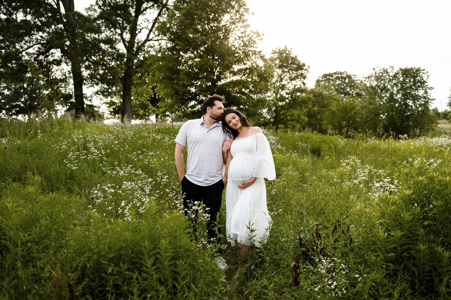 Expectant couple standing together in a field during an outdoor maternity photography session in Raleigh NC