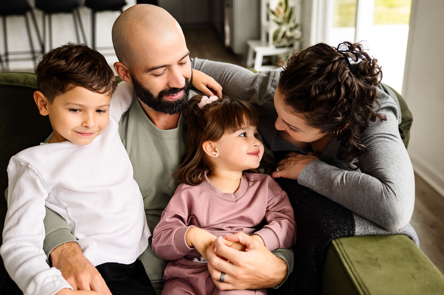 Parents sitting with their children on the couch during a natural in-home family photography session in Apex North Carolina