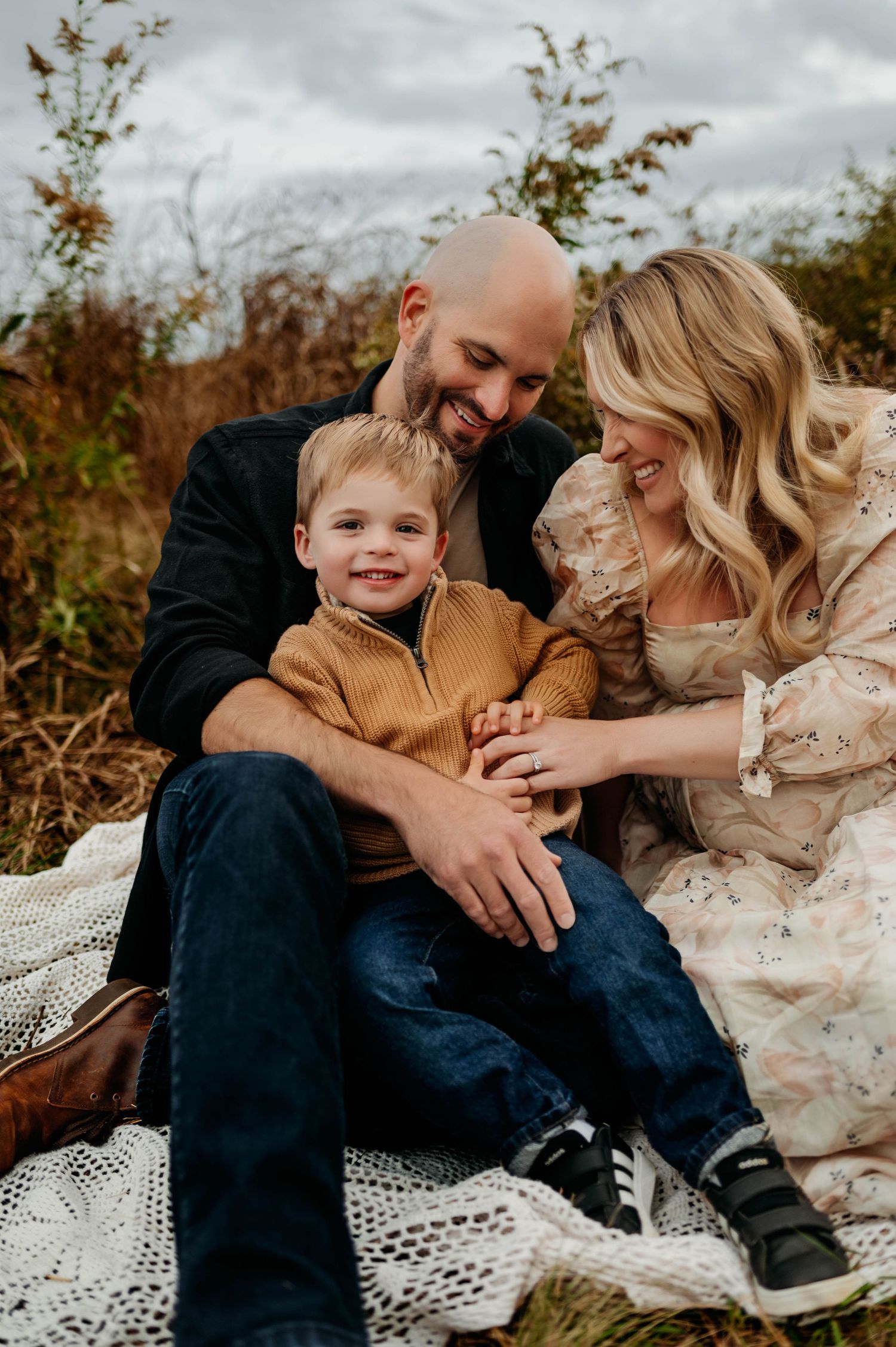 A loving family shares a candid moment together while sitting on a blanket outdoors chapel hill maternity photographer
