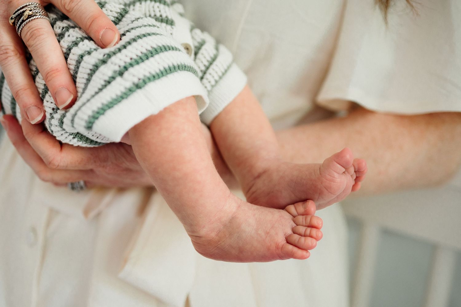 Close-up detail of a newborn baby's tiny feet while being held by a parent during an in-home newborn photography session in Raleigh NC