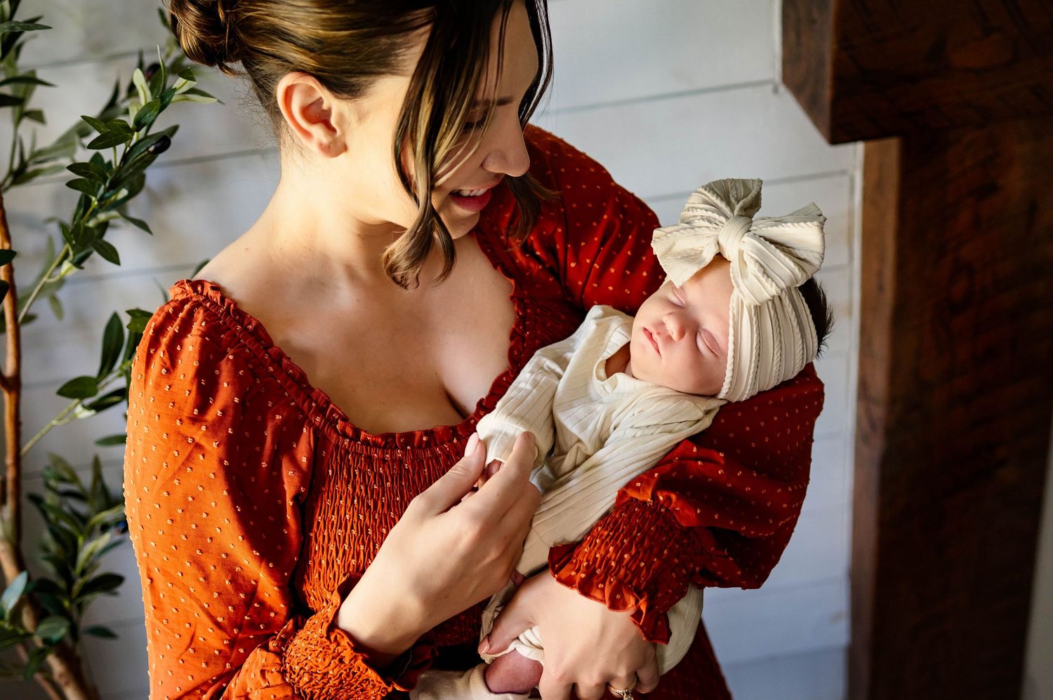 Mother holding her sleeping newborn daughter during an in-home newborn photography session in Raleigh NC