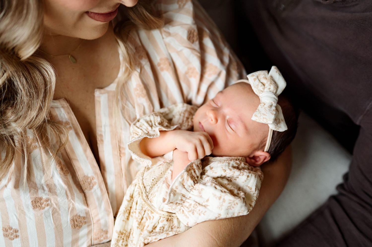 Close-up of a sleeping newborn girl wrapped in neutral tones during a relaxed in-home photography session in Raleigh NC