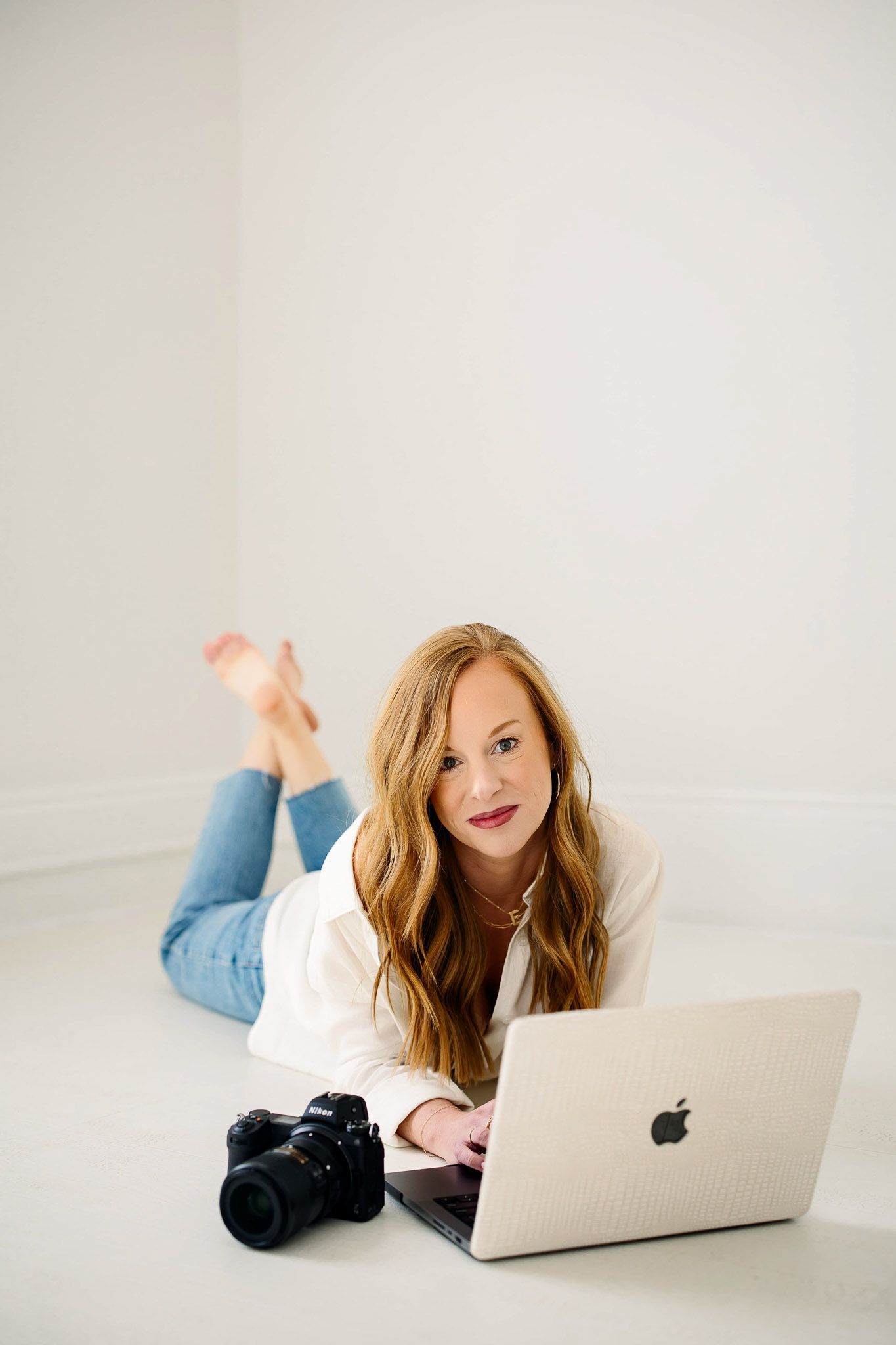 Emma Branch Raleigh family photographer using laptop beside camera in bright natural light studio