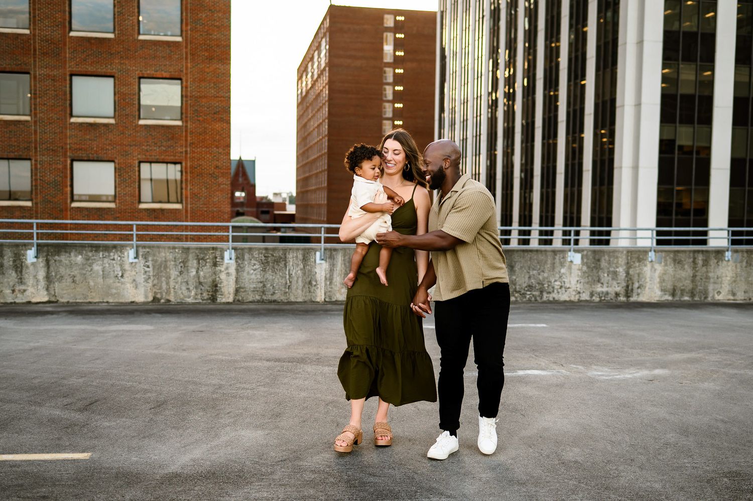 Parents walking together with their toddler during a rooftop family photography session in downtown Raleigh