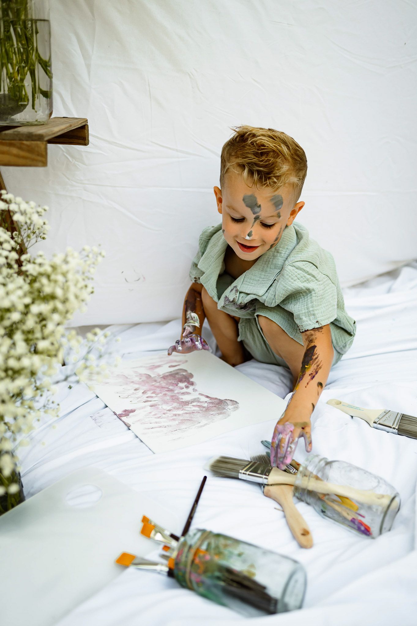 Young boy painting on paper during a creative outdoor family photography session in Wake Forest NC