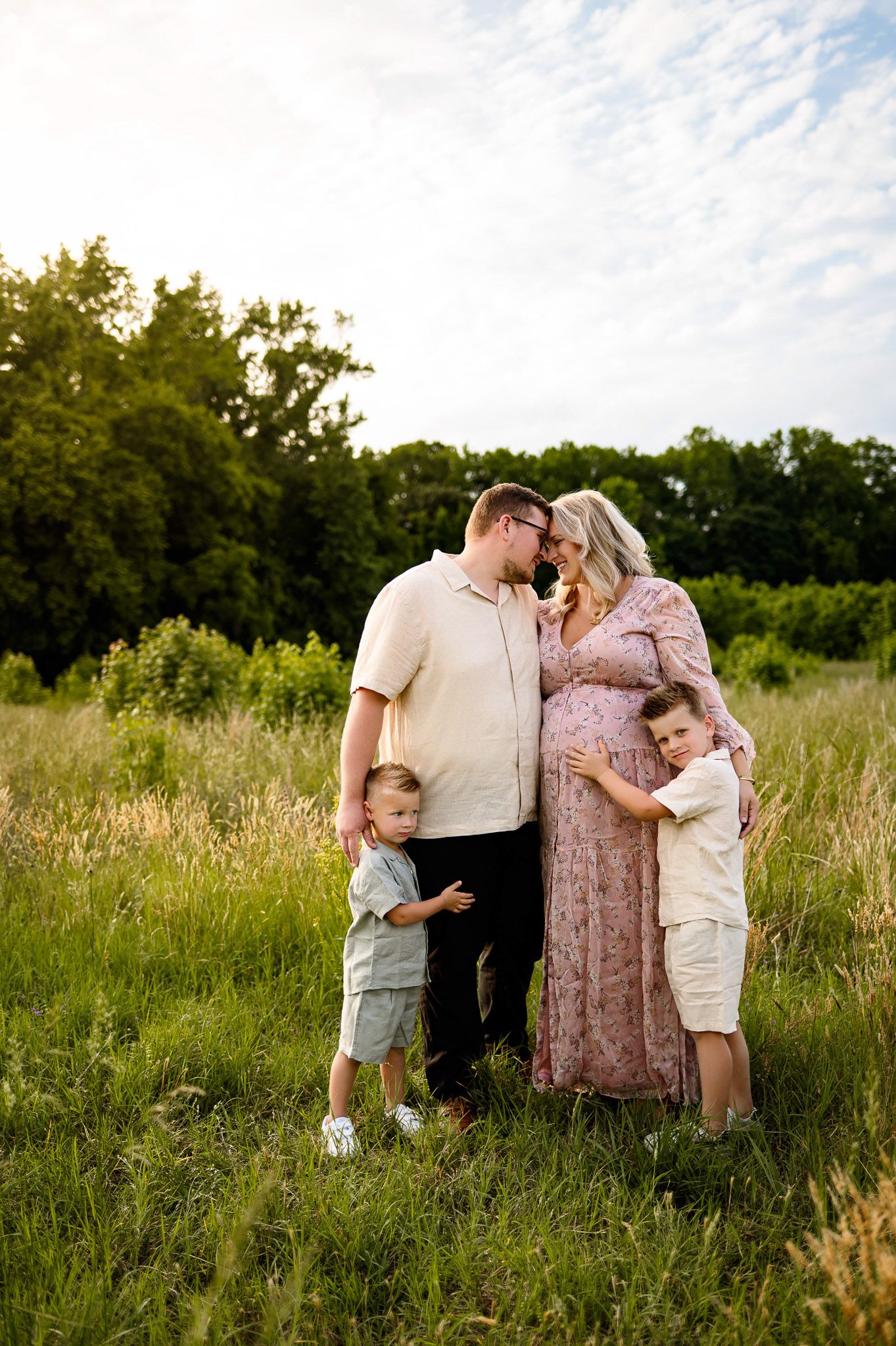 Raleigh maternity photographer capturing a family embracing their pregnant mother in a grassy field