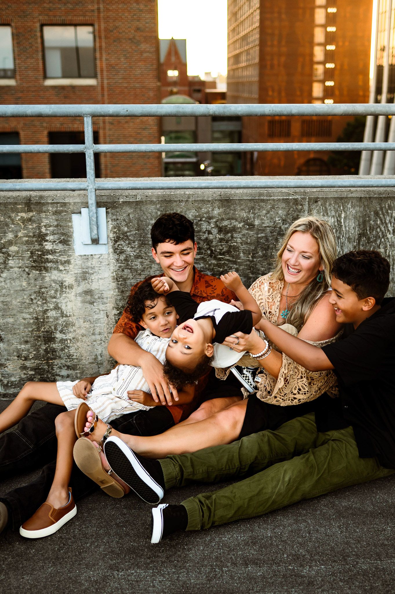 Mother and children laughing together while sitting on a rooftop during a family photography session