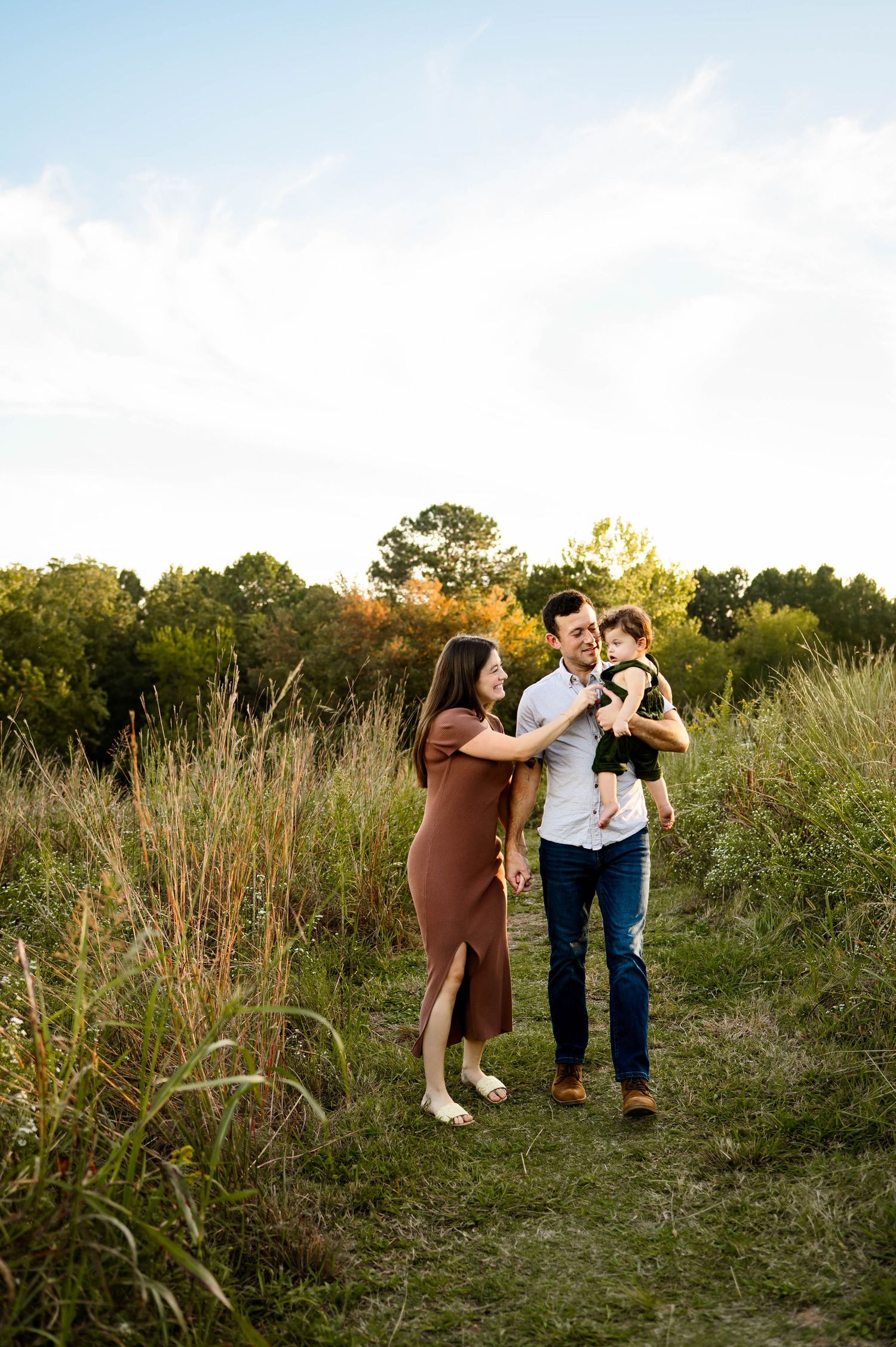 Family walking along a grassy trail during a golden hour family photography session at the North Carolina Museum of Art Park in Raleigh