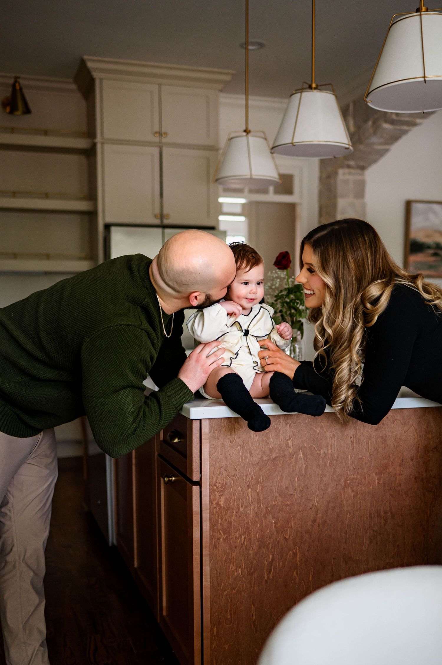 Family shares an intimate moment together in their home while father kisses daughter on cheek with raleigh family photographer