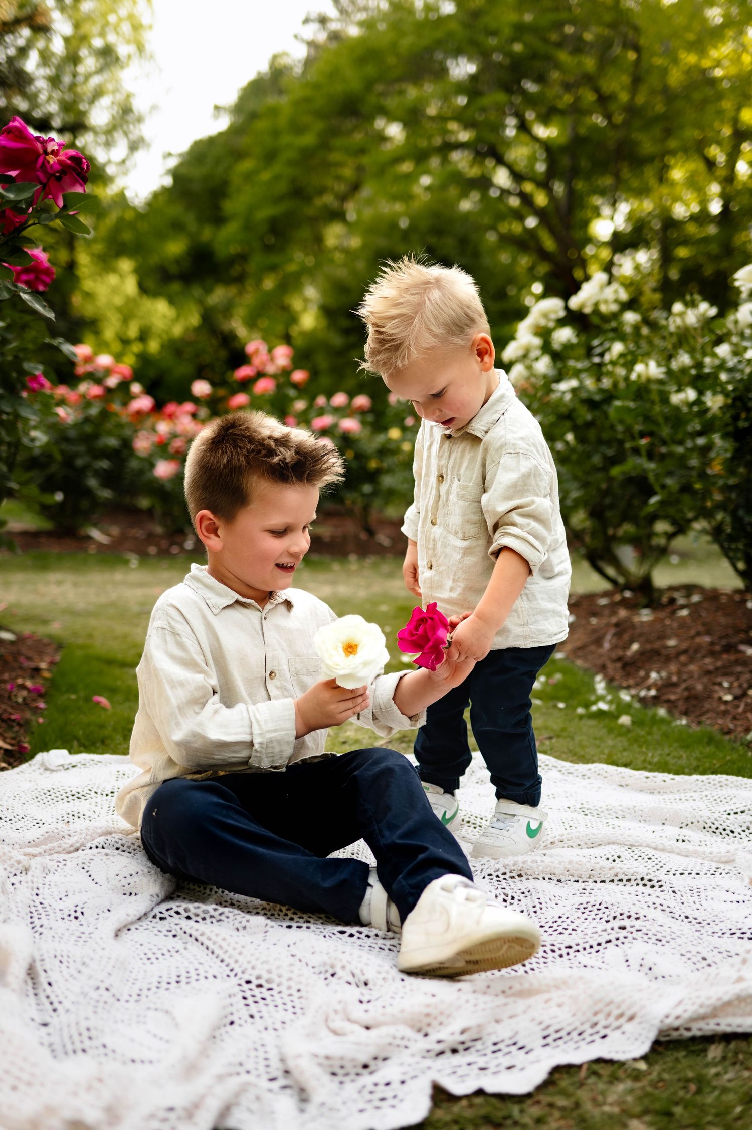 Two young brothers sharing flowers during a spring family photography session in Raleigh with Emma Branch