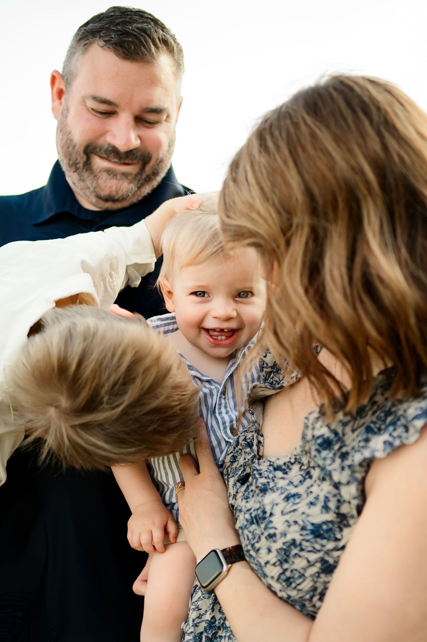 Smiling baby held by parents during natural light Raleigh family photography session