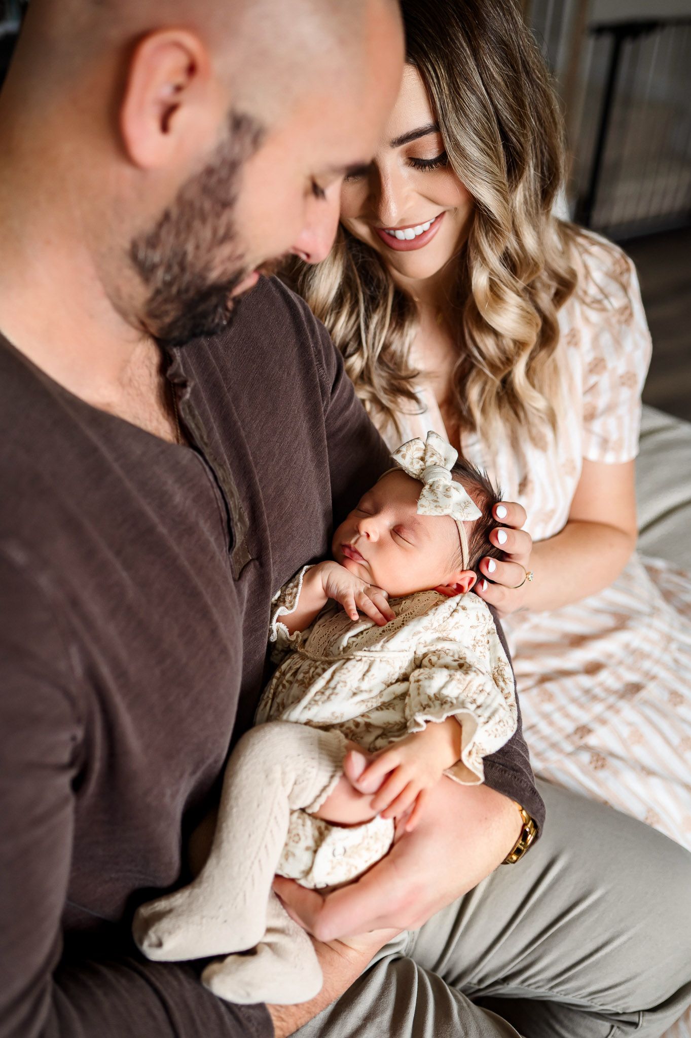 Parents smiling down at their newborn baby during an intimate in-home newborn photography session