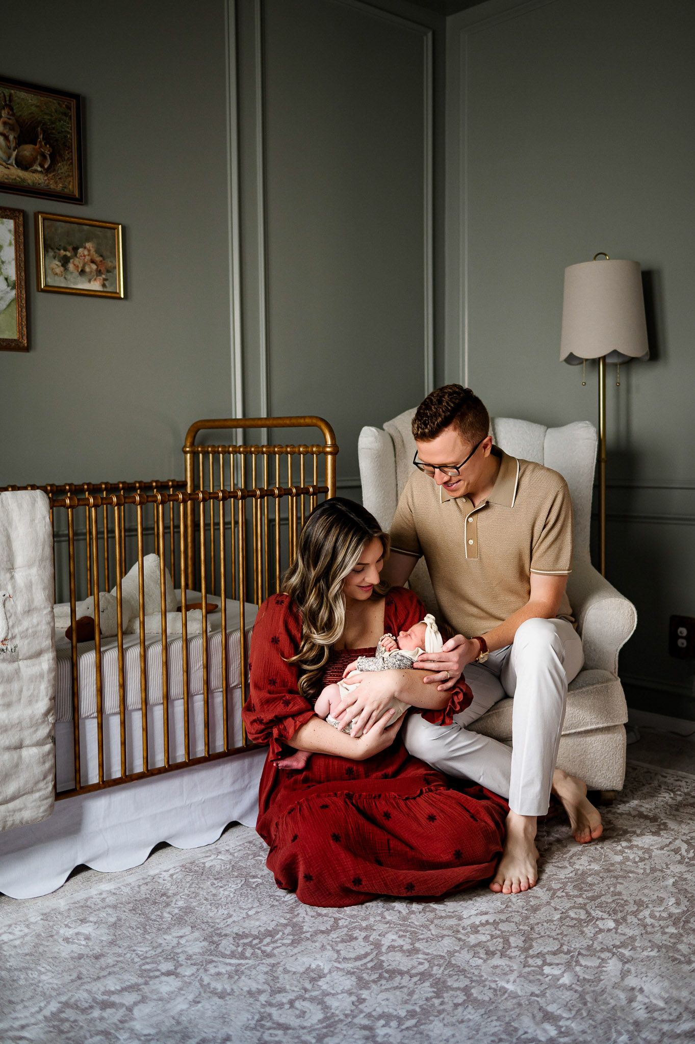 Parents sitting together in the nursery holding their newborn during a relaxed in-home lifestyle newborn session