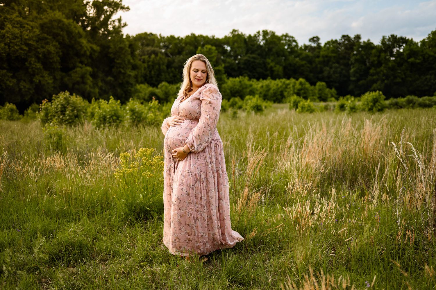 Pregnant mother standing in a grassy field during an outdoor maternity photography session near Raleigh North Carolina