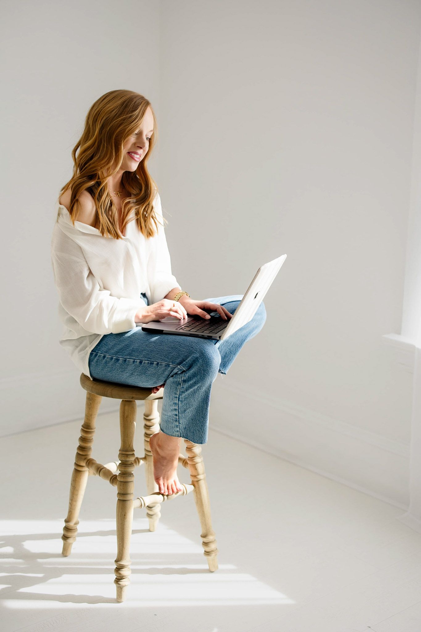 Raleigh family photographer Emma Branch working on laptop in bright natural light studio