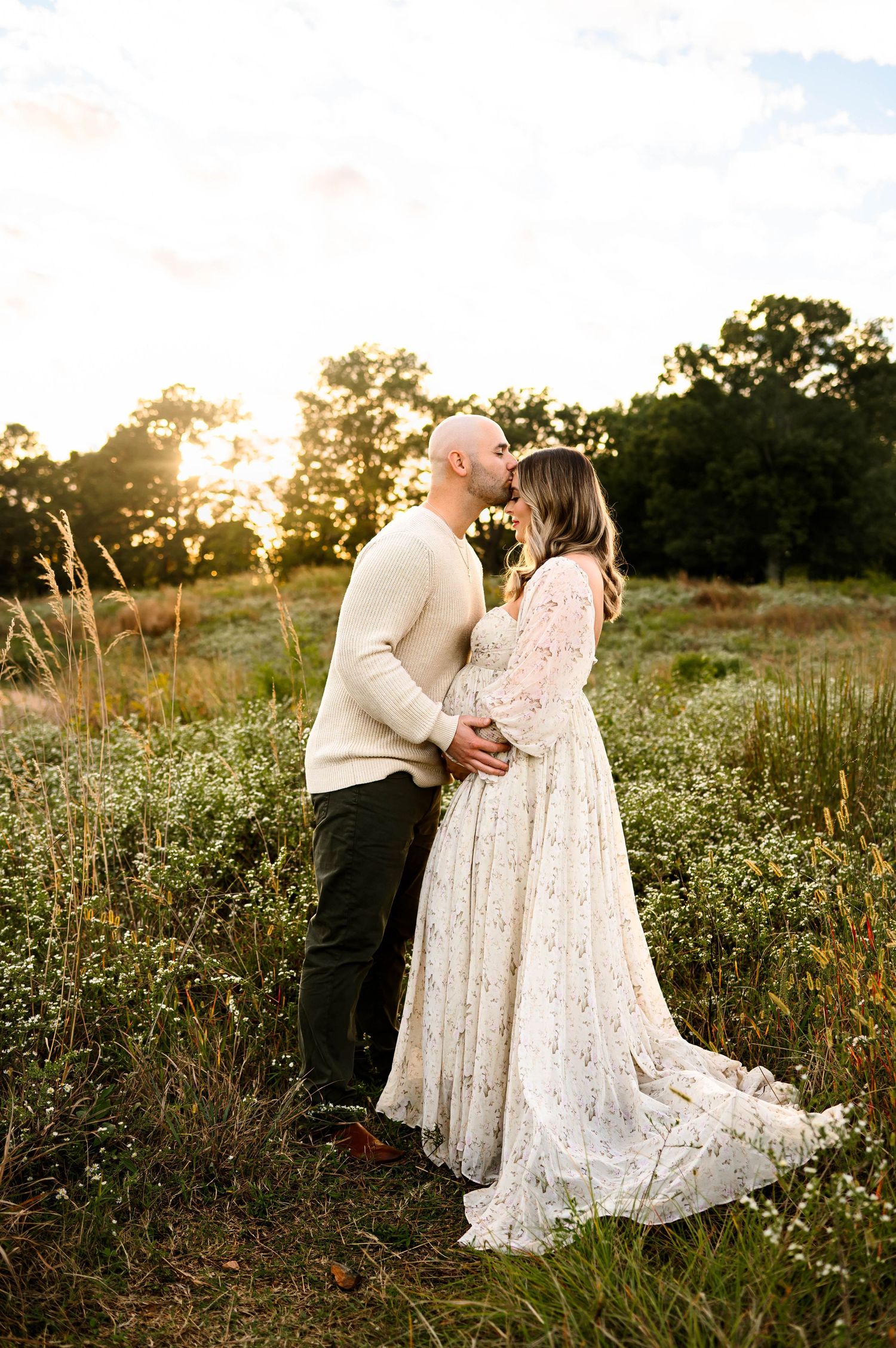 Couple embracing during a golden hour maternity photography session in an open field in Raleigh