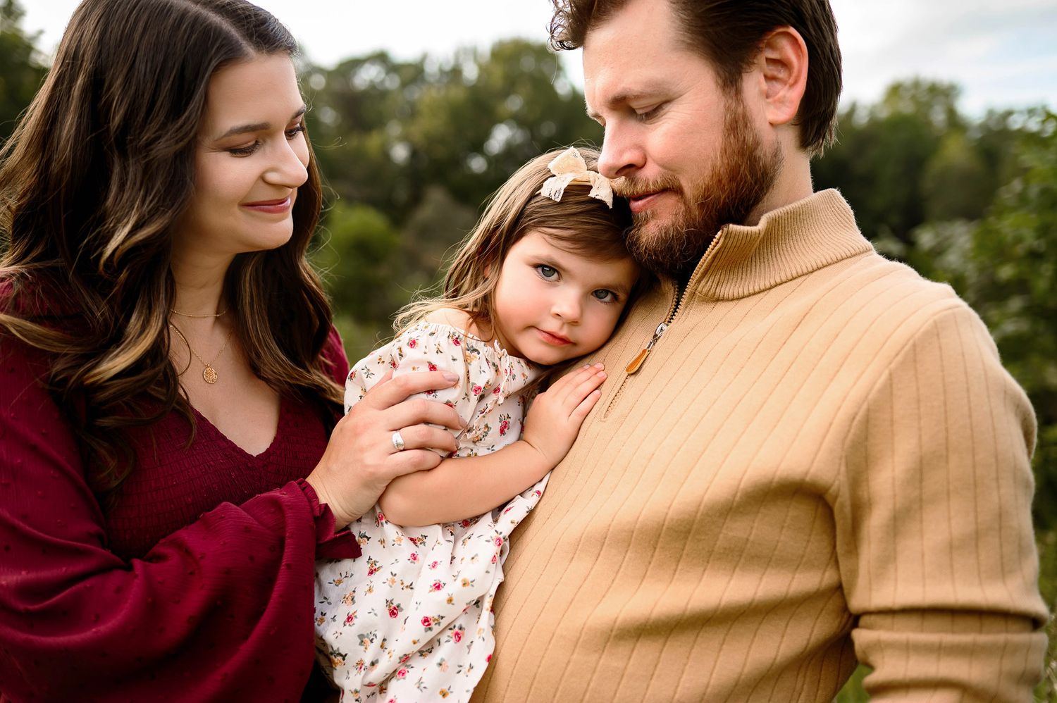 Close up maternity family portrait with mother father and young daughter during outdoor Raleigh maternity photography session