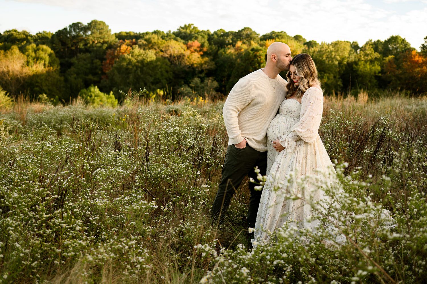 Expecting parents embracing during outdoor photography session in a wildflower field with Raleigh maternity photographer