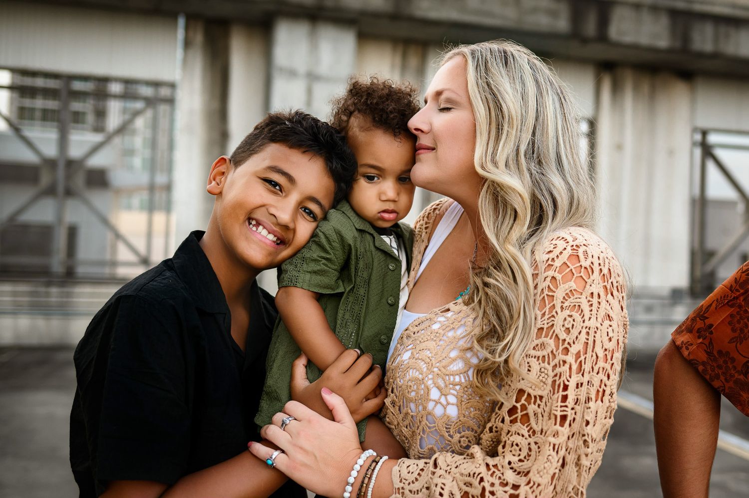 Mother holding her baby while her older son leans in during a natural family photography session