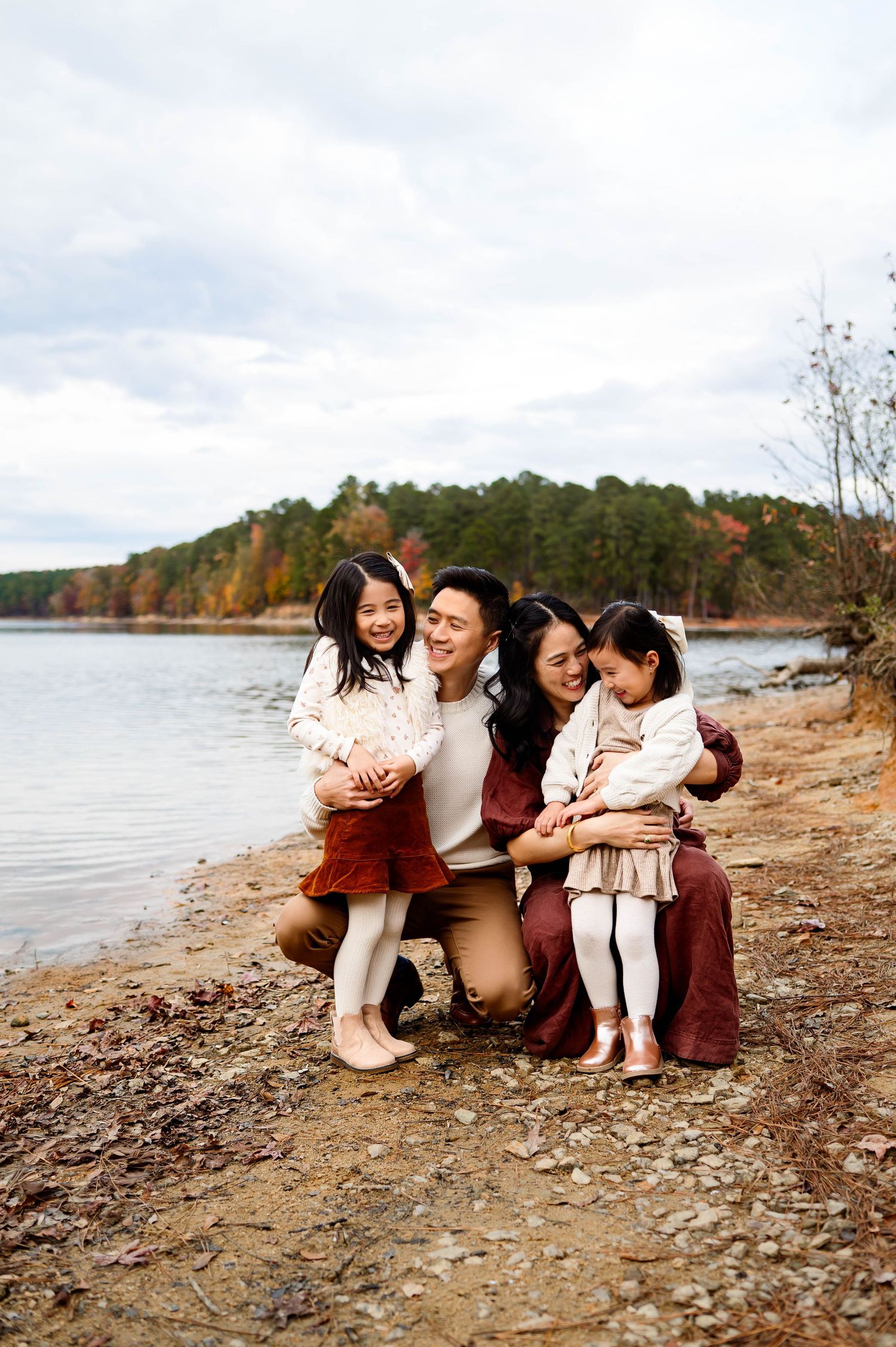 Family sitting together along the shoreline during a fall family photography session at Falls Lake near Raleigh NC
