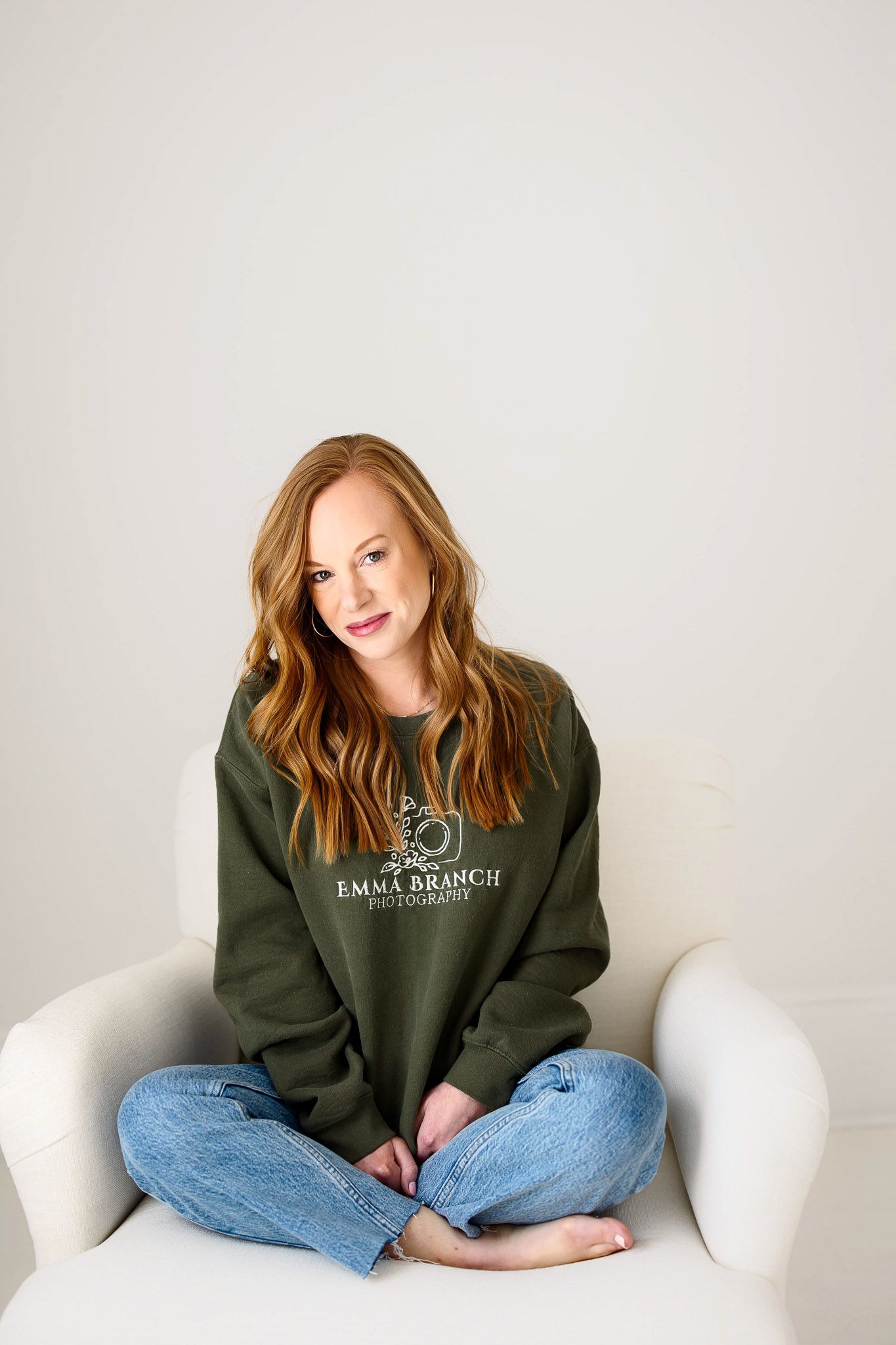 Raleigh family photographer sitting in chair wearing green Emma Branch Photography sweatshirt