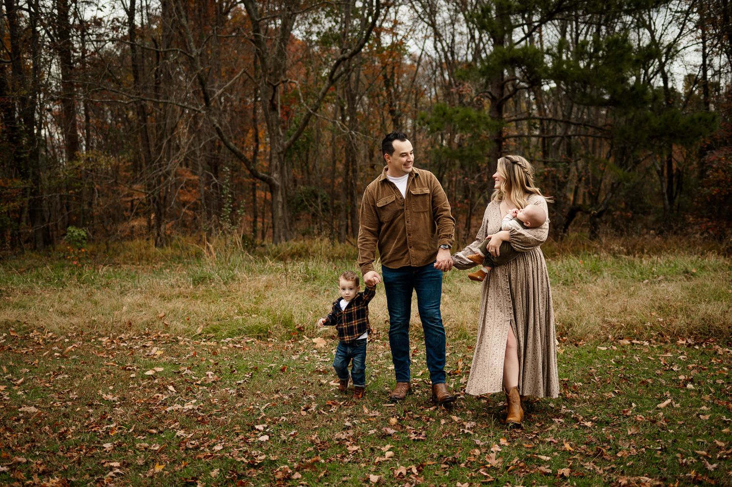 Family walking together through fall leaves during an outdoor family photography session in Raleigh NC