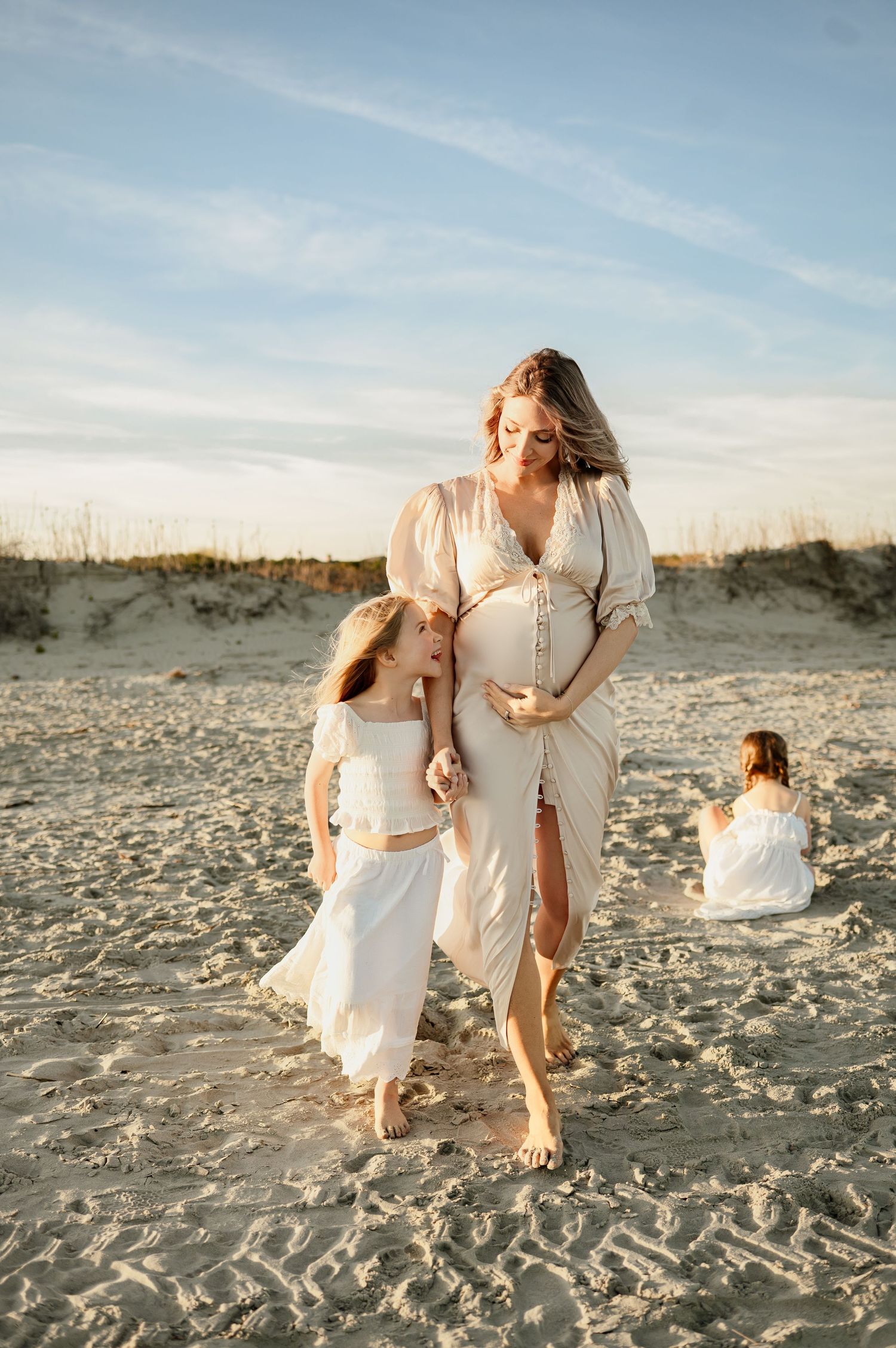 Daughter smiles playfully up at her mother while walking together during a maternity photography session near Raleigh NC