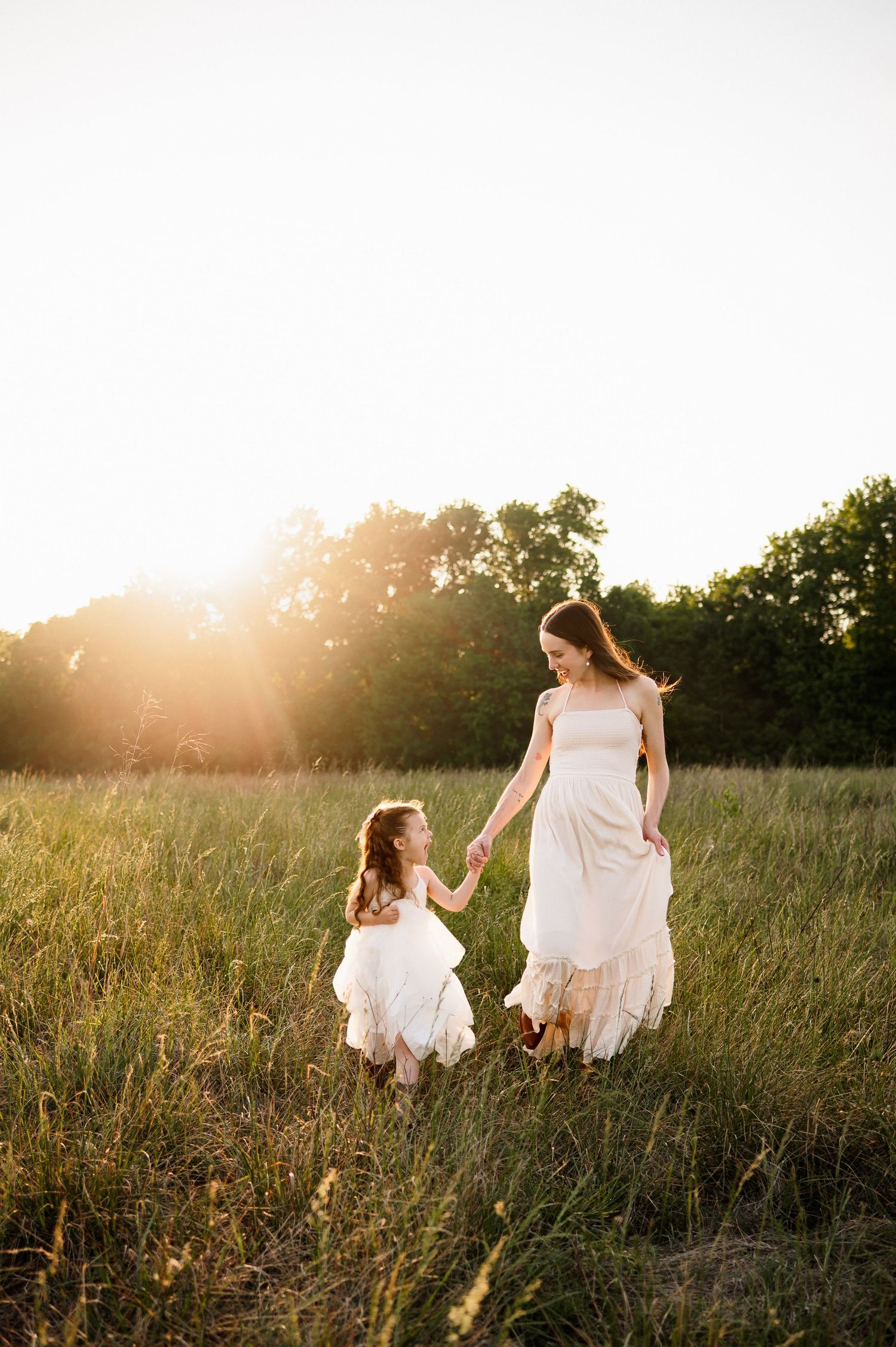 Mother and daughter walking hand in hand through a field during golden hour family photos in Raleigh NC