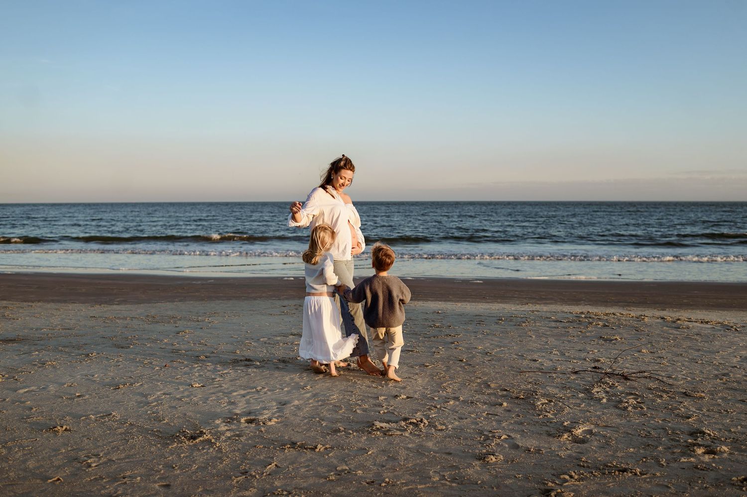 Raleigh family photographer captures mother with children walking along the beach during a sunset maternity photography session