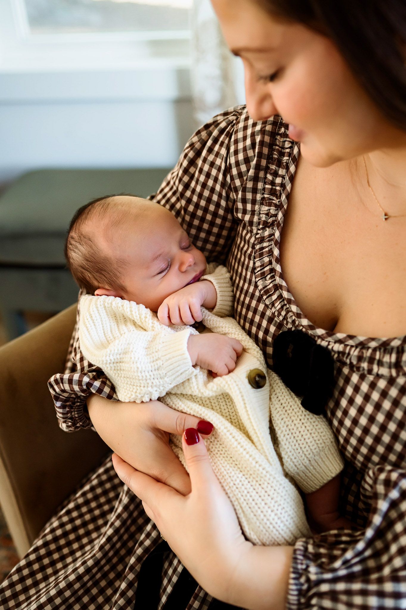 Mother cradling her newborn baby in soft natural light during a lifestyle newborn photography session