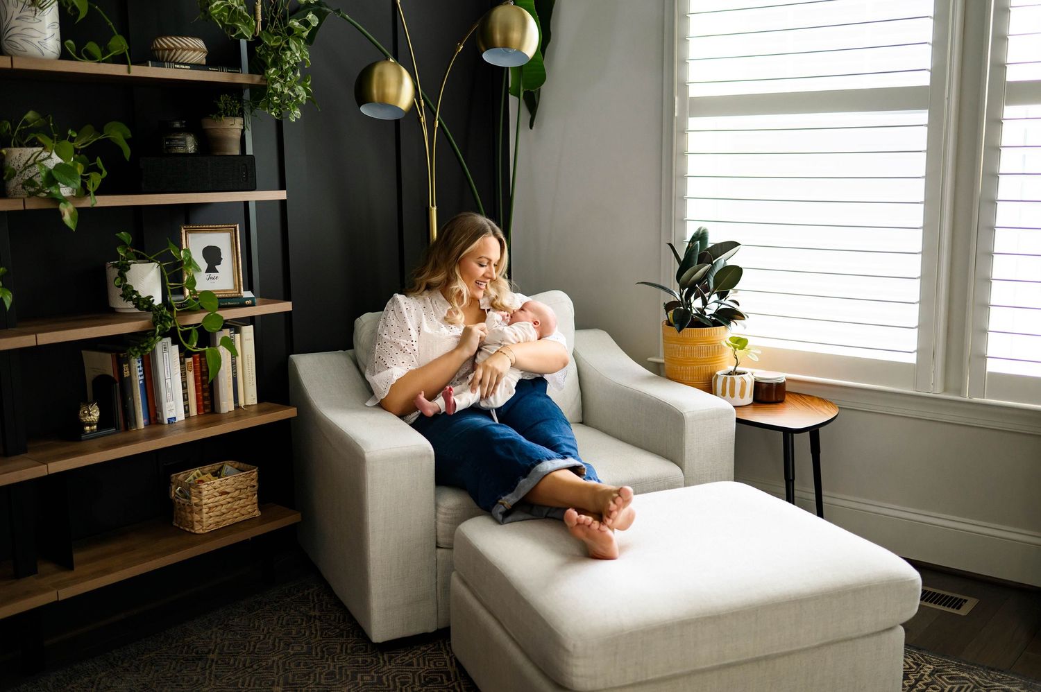 Mother holding her baby during an in-home newborn photography session in Raleigh NC seated in a cozy chair