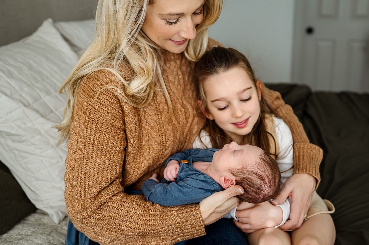 Mother and daughter cuddling a newborn baby together during a relaxed lifestyle newborn photography session