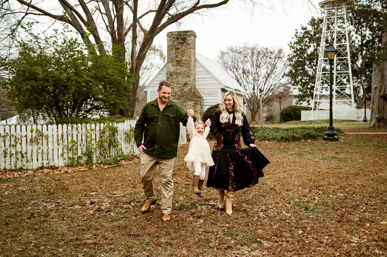 Parents swinging their daughter between them while walking during an outdoor family photography session in Knightdale NC