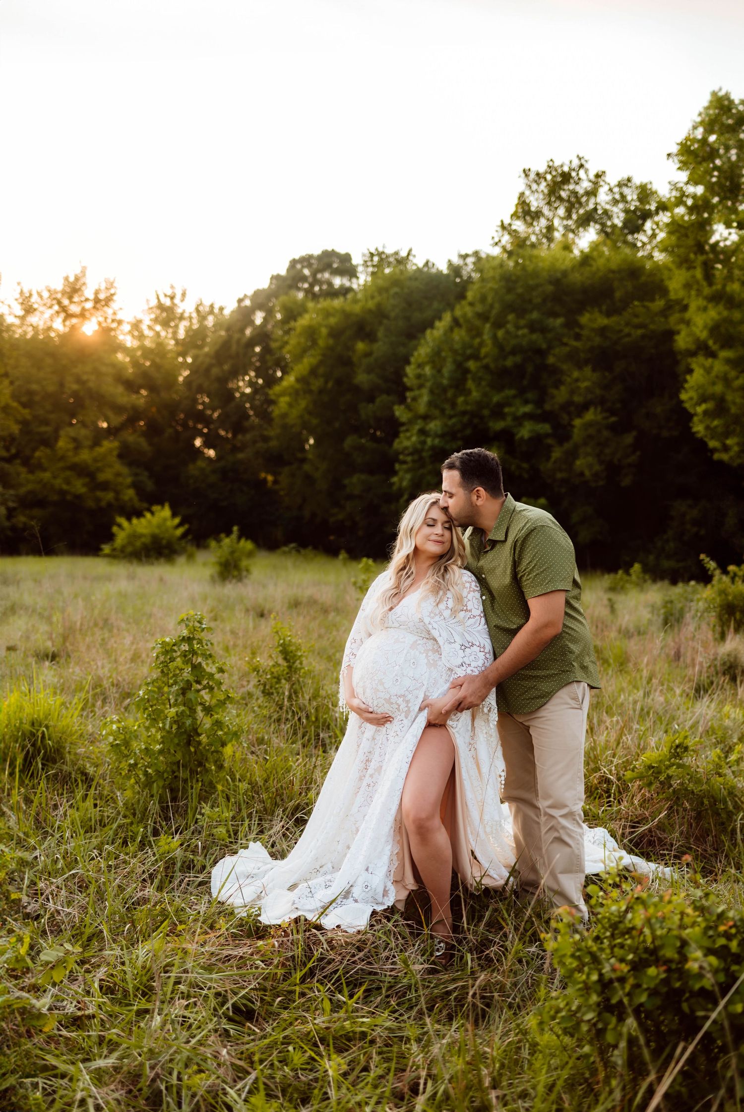 A couple embraces during a sunset maternity photoshoot in a wildflower meadow for intimate photography session with Emma Branch Photography