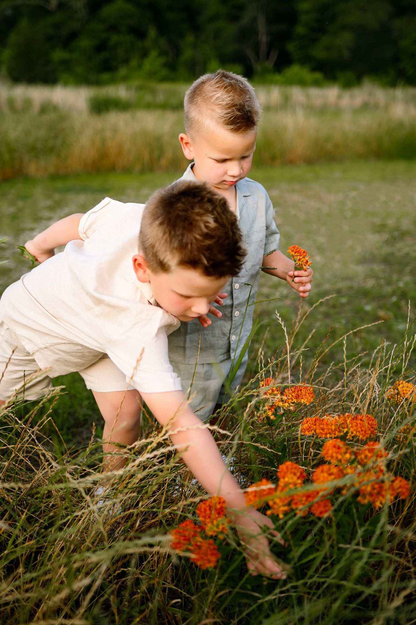 Young siblings picking wildflowers during a maternity photography session with their growing family in Raleigh NC