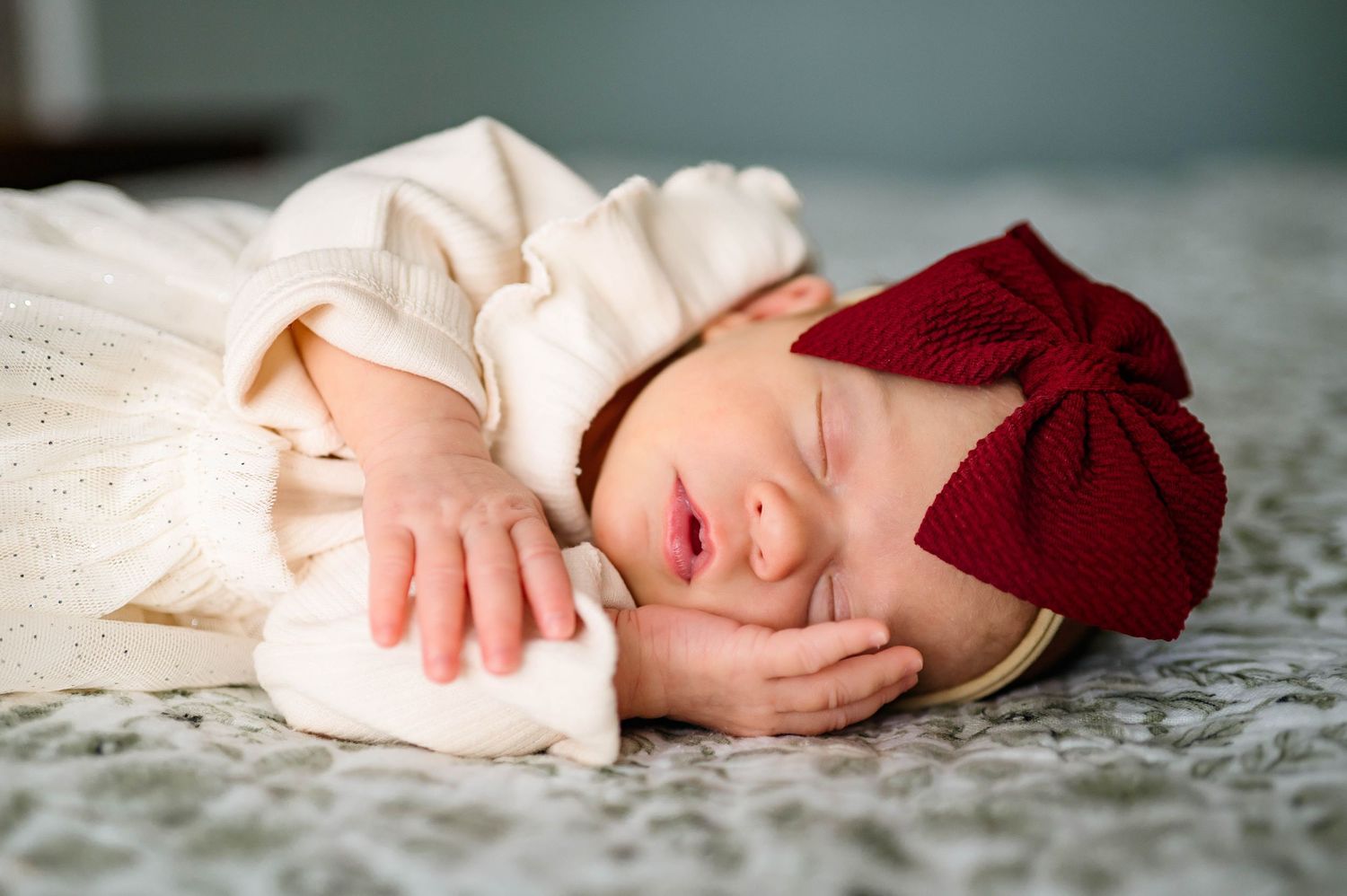 Sleeping newborn girl wearing a bow during an in-home newborn photography session with Raleigh newborn photographer