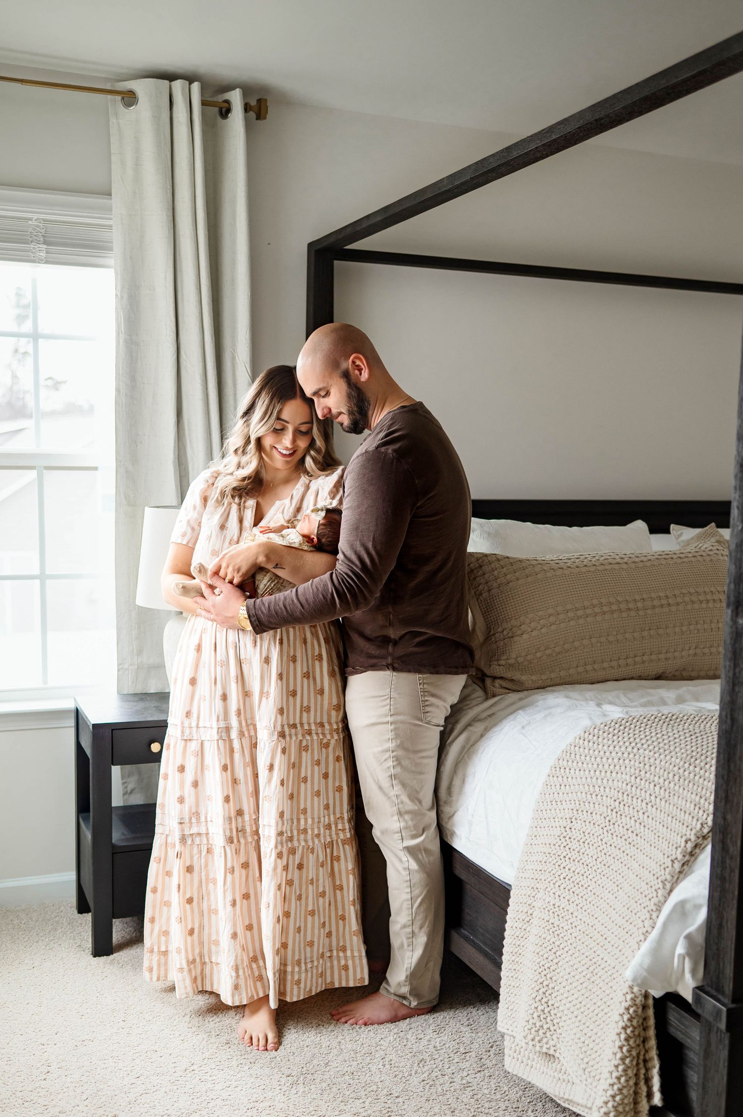 Parents holding their newborn daughter together during a natural lifestyle newborn session in Raleigh NC