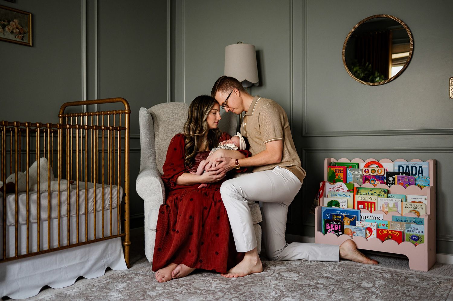 Parents cuddling their baby beside crib in softly lit nursery during in-home photography session with Raleigh newborn photographer